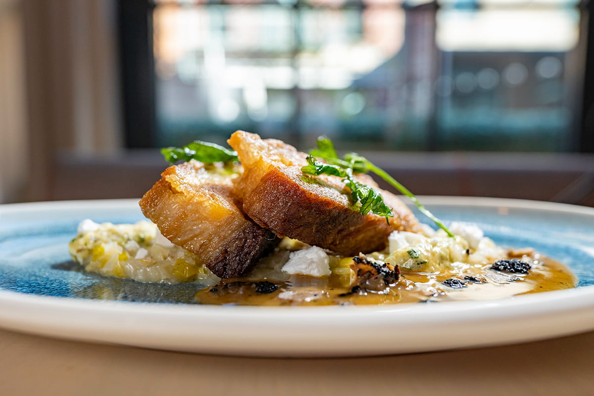 FIG & OLIVE - Beeler’s Pork Belly Fondant Leeks, Crumbled Feta Cheese, Gribiche Sauce, Truffle Natural Jus