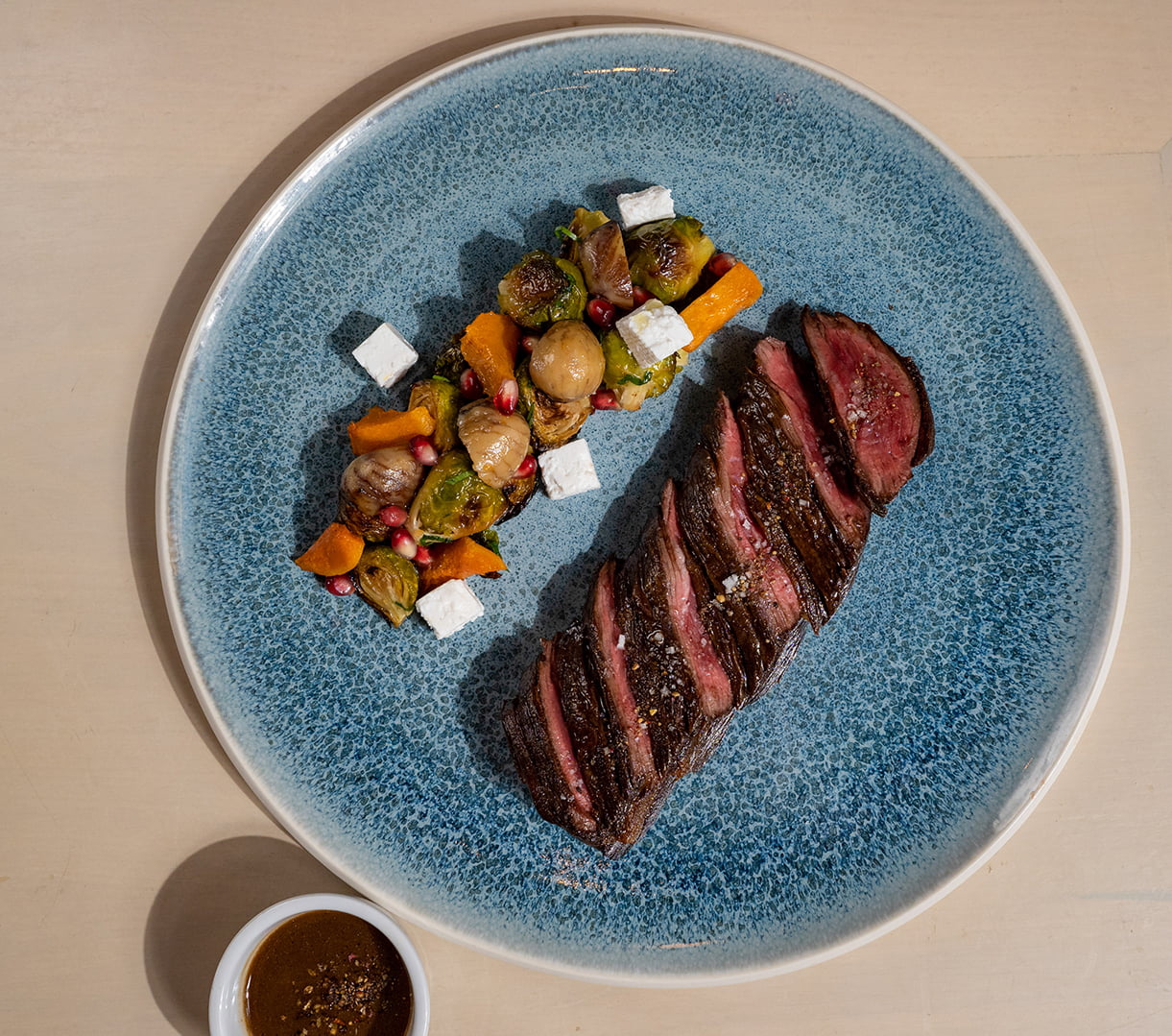 FIG & OLIVE - Grass-Fed Hanger Steak Roasted Brussels Sprouts & Squash, Confit Chestnuts, Feta Cheese, Pomegranate, Candied Bacon, ‘Sauce au Poivre’