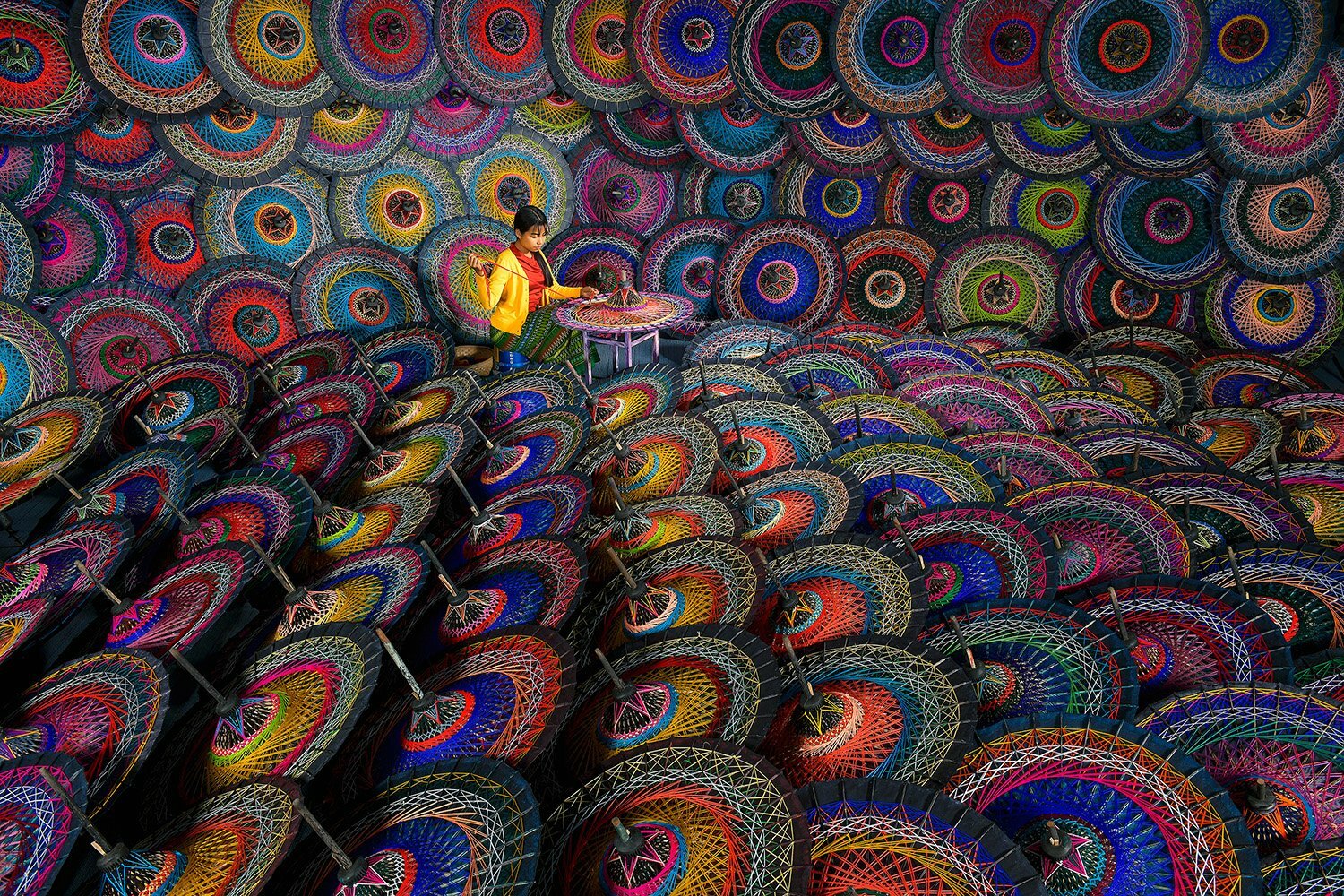 Colourful Life - Photographer Name: Saravut Whanset. A young woman in an umbrella workshop, making a traditional Burmese parasol in Mandalay, Myanmar – handmade using bamboo and cotton. Copyright: © Saravut Whanset, Thailand, Shortlist, Open, Travel, 2022 Sony World Photography Awards