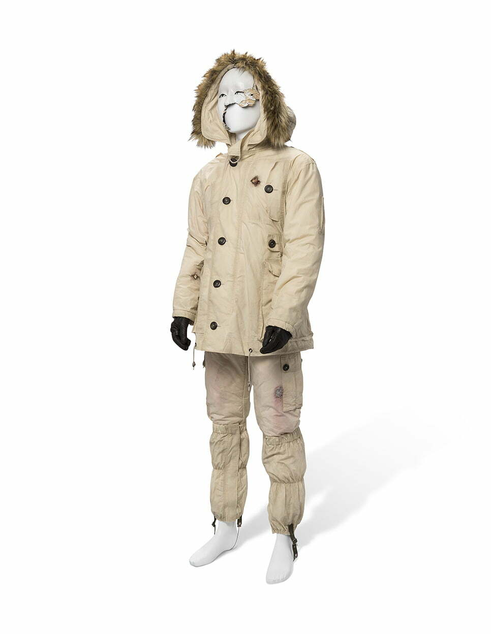 A FRACTURED MASK AND COSTUME WITH BULLET HOLES, WORN BY RAMI MALEK AS SAFIN, DESIGNED BY SUTTIRAT ANNE LARLARB WITH COLOURED CONCEPT COSTUME DESIGN PRINT, SIGNED BY SUTTIRAT ANNE LARLARB