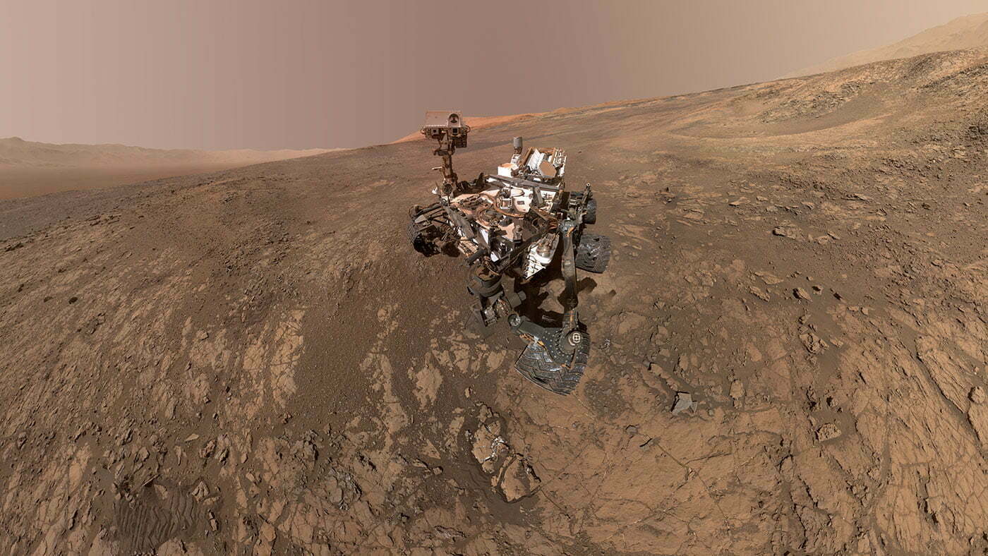 This self-portrait of NASA's Curiosity Mars rover shows the vehicle on Vera Rubin Ridge, which it's been investigating for the past several months. Directly behind the rover is the start of a clay-rich slope scientists are eager to begin exploring. In the coming week, Curiosity will begin to climb this slope. North is on the left and west is on the right, with Gale Crater's rim on the horizon of both edges.