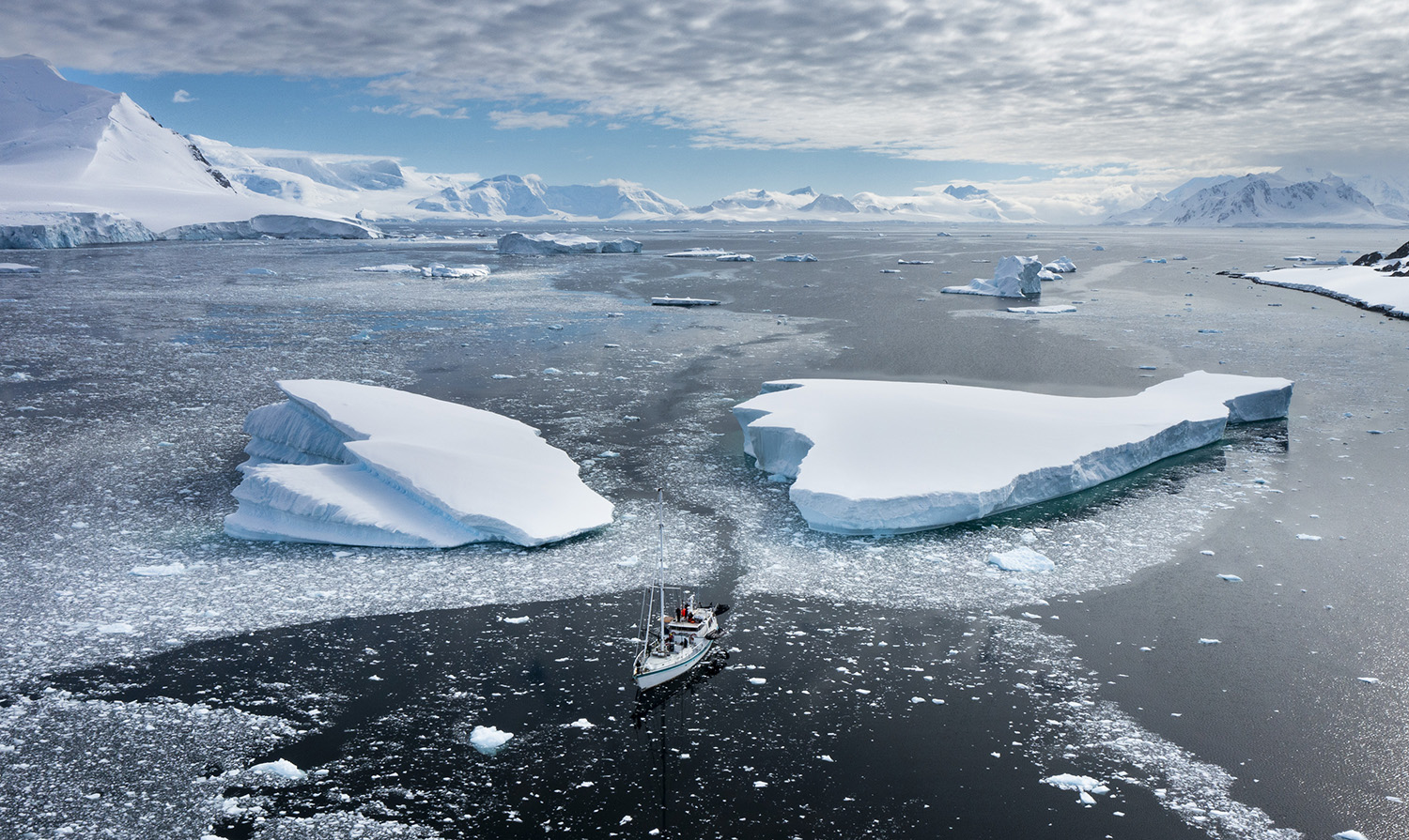 Aerial shot of Australis sailing between two large ice sheets.