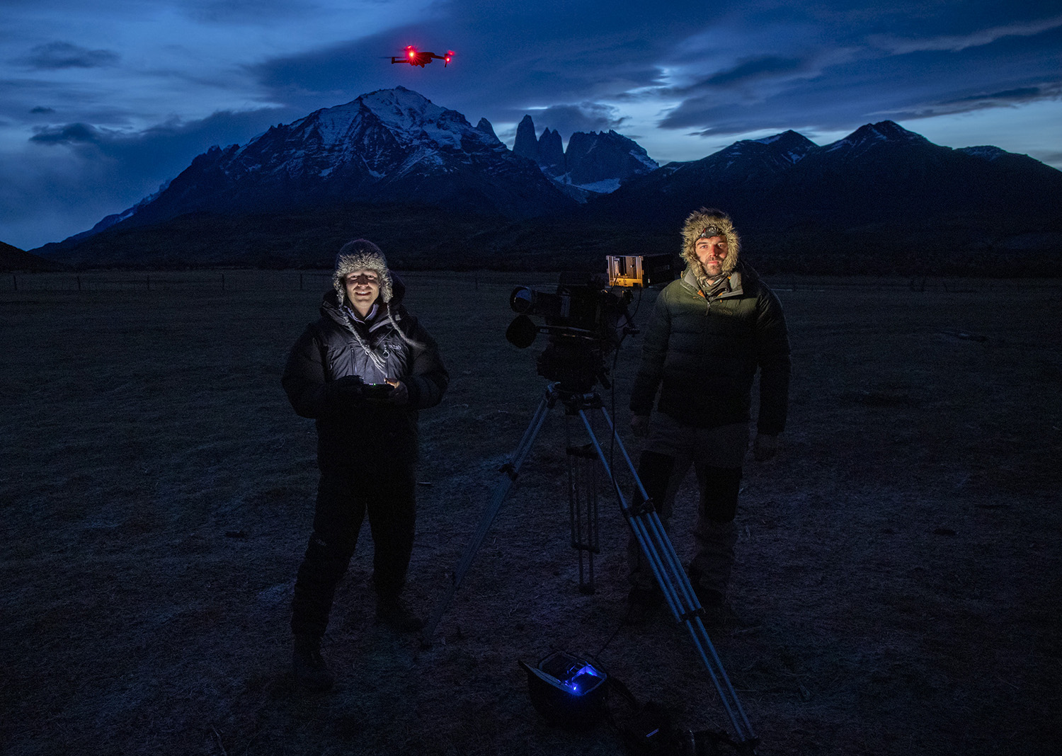 Bertie Gregory and Sam Stewart standing with camera in front of the mountains.