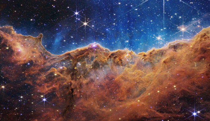 Featured in the IMAX® documentary DEEP SKY,  the Webb Telescope reveals the glittering landscape of the “Cosmic Cliffs”, the edge of a nearby, young, star-forming region called NGC 3324 in the Carina Nebula roughly 7,600 light-years away.