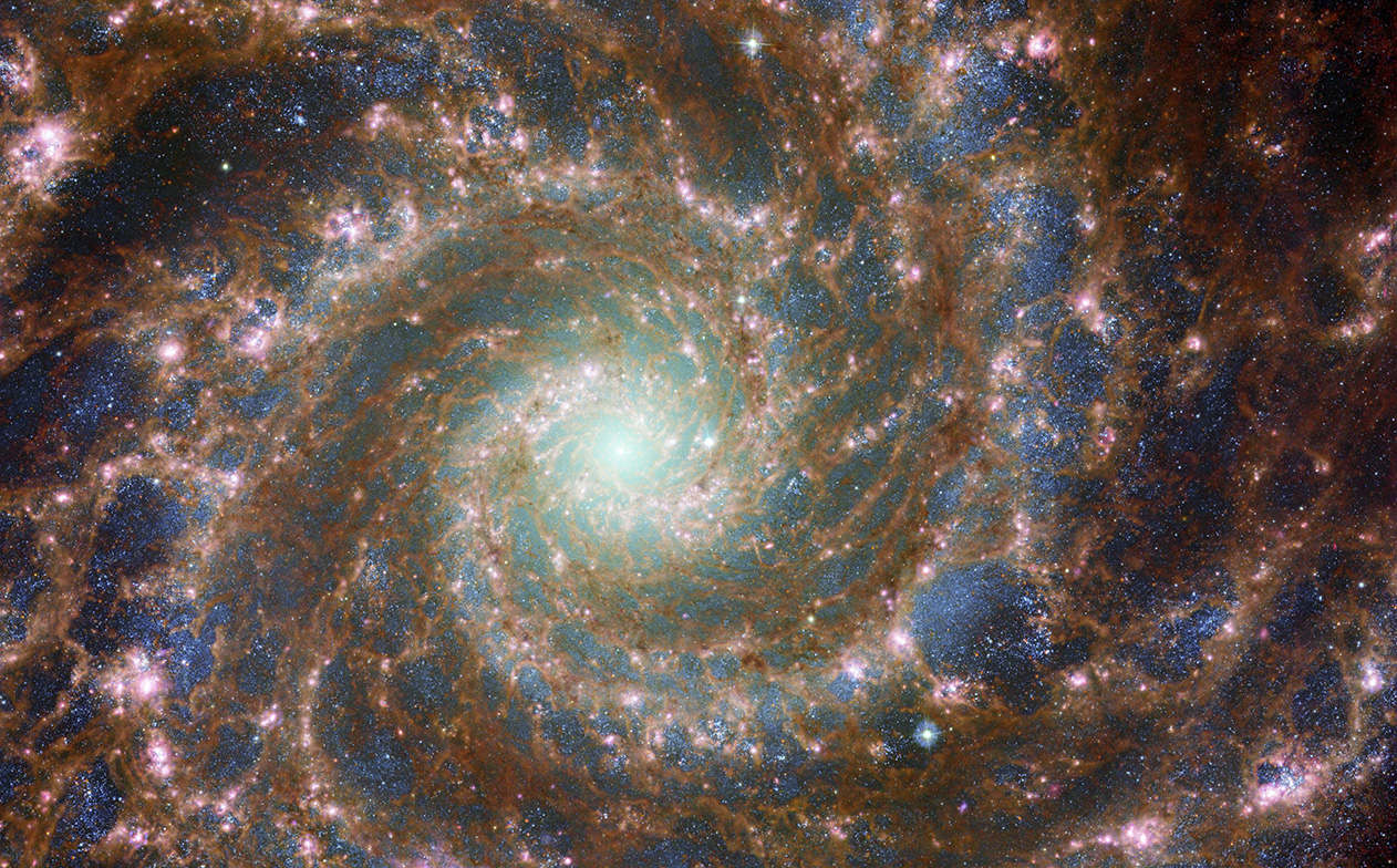 Featured in the IMAX® documentary DEEP SKY,  M74 shines at its brightest in this combined optical/mid-infrared image, featuring data from both the Hubble Telescope and JWST.