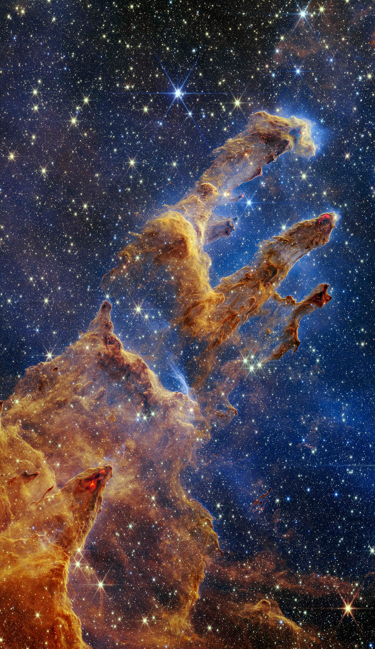 Featured in the IMAX® documentary DEEP SKY, the Pillars of Creation are set off in a kaleidoscope of color in NASA’s James Webb Space Telescope’s near-infrared-light view. The pillars look like arches and spires rising out of a desert landscape, but are filled with semi-transparent gas and dust, and ever changing. This is a region where young stars are forming – or have barely burst from their dusty cocoons as they continue to form.