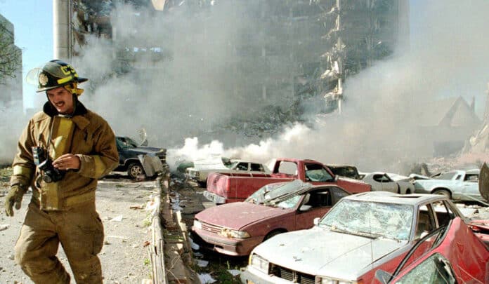 An Oklahoma City fireman walks near explosion-damaged cars on the north side of the Alfred Murrah Federal Building in Oklahoma City after a car bomb explosion on April 19, 1995, in Oklahoma City, Okla.