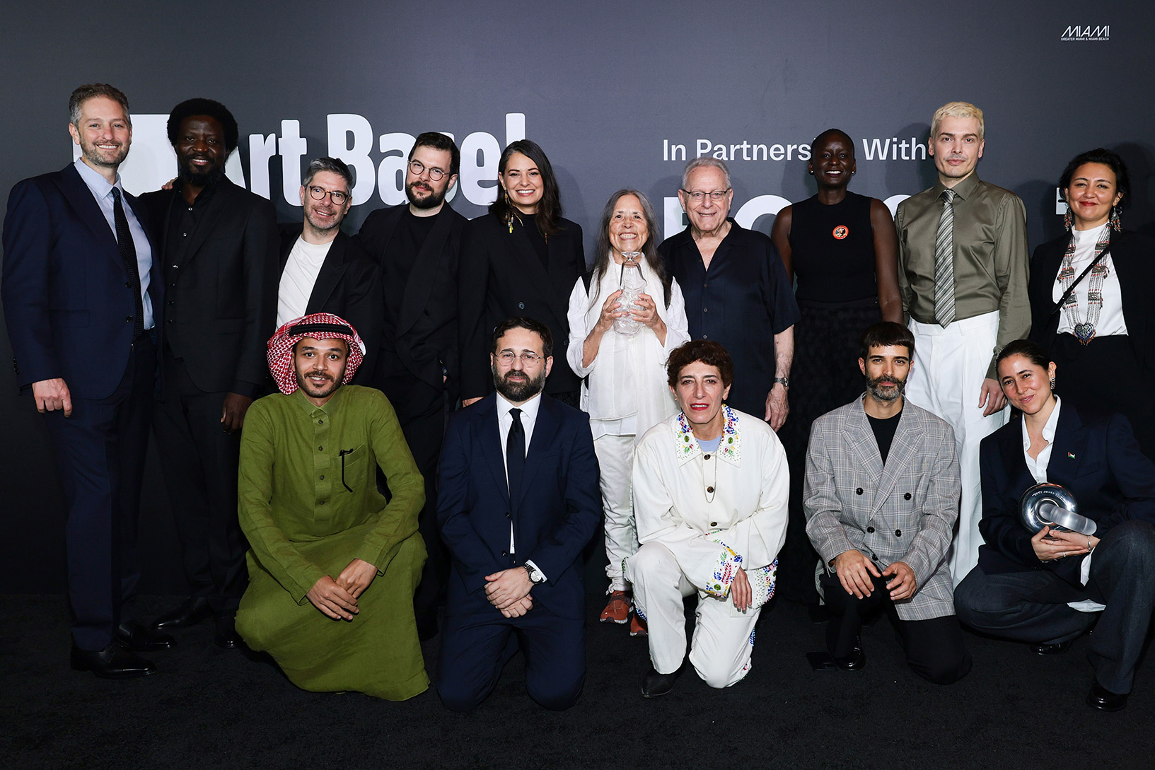 MIAMI BEACH, FLORIDA - DECEMBER 04: (L-R) Noah Horowitz, Ibrahim Mahama, Mohammad Al Faraj, Alessio Antoniolli, Robert Leckie, Vincenzo De Bellis, Candice Hopkins, Cecilia Vicuna, Nairy Baghramian, Joel Wachs, Marie Helene-Pereira, Andrea Trimarchi, Simone Farresin, Meriem Bennani, Saodat Ismailova and Marco Falcioni attend during the Art Basel Awards Night in Miami Beach at New World Symphony on December 04, 2025 in Miami Beach, Florida.