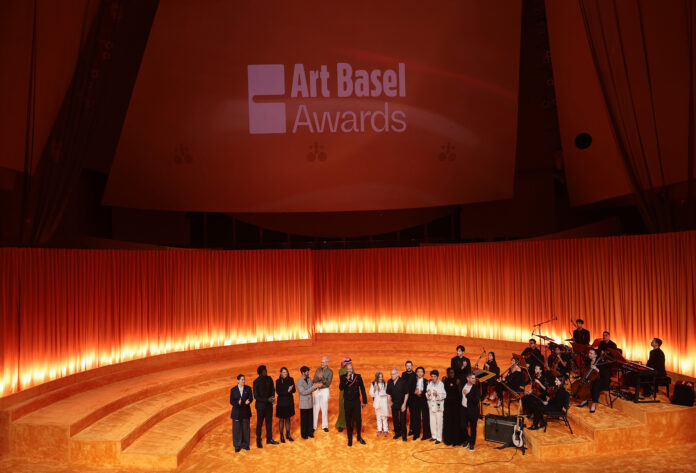 MIAMI BEACH, FLORIDA - DECEMBER 04: (L-R) Meriem Bennani, Ibrahim Mahama, Candice Hopkins, Andrea Trimarchi, Cecilia Vicuna, Joel Wachs, Swizz Beatz, Simone Farresin, Mohammad Al Faraj, Robert Leckie, Saodat Ismailova, Nairy Baghramian, Marie Helene-Pereira and Alessio Antoniolli speaks during the Art Basel Awards Night in Miami Beach at New World Symphony on December 04, 2025 in Miami Beach, Florida.